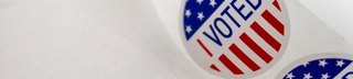A roll of "I Voted" stickers on a white desk facing left