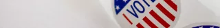 A roll of "I Voted" stickers on a white desk facing left